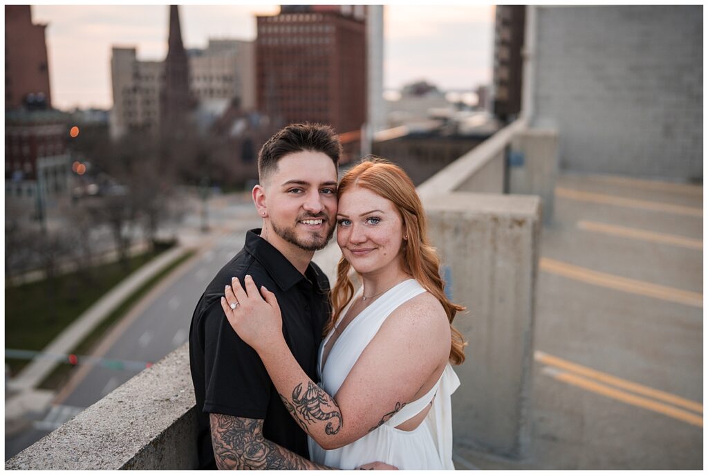 Emma and Nick Pose on top of a parking garage in downtown Buffalo NY. You can see the city streets below them in the background