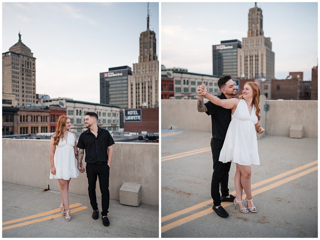 Emma and Nick look at each other and laugh while posing for their engagement photos on top of a parking garage in downtown Buffalo NY