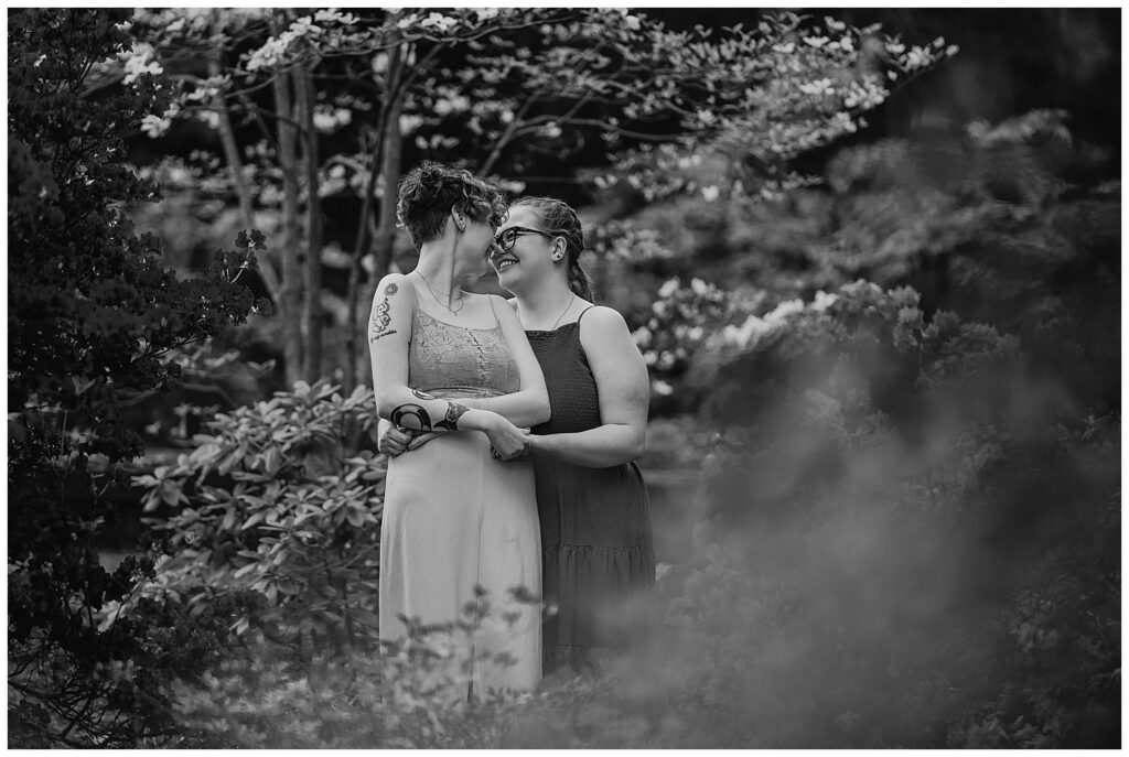 a black and white image of cas and kaylie standing wrapped around each other in highland park