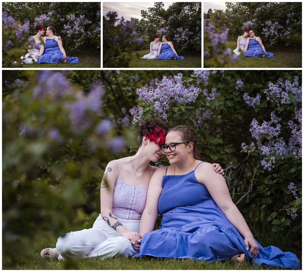 Cas and Kaylie sit beside each other in the grass of highland park. Purple lilacs are in full bloom behind them.